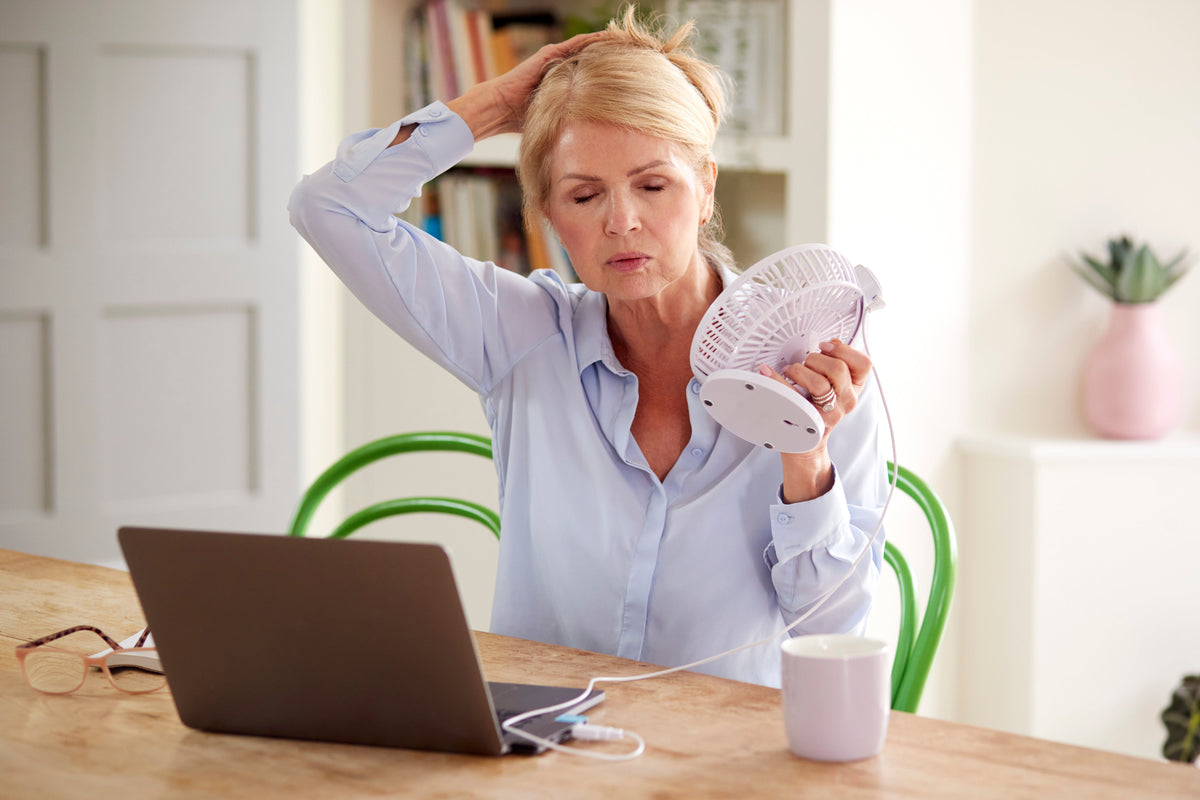 woman holding fan on her face