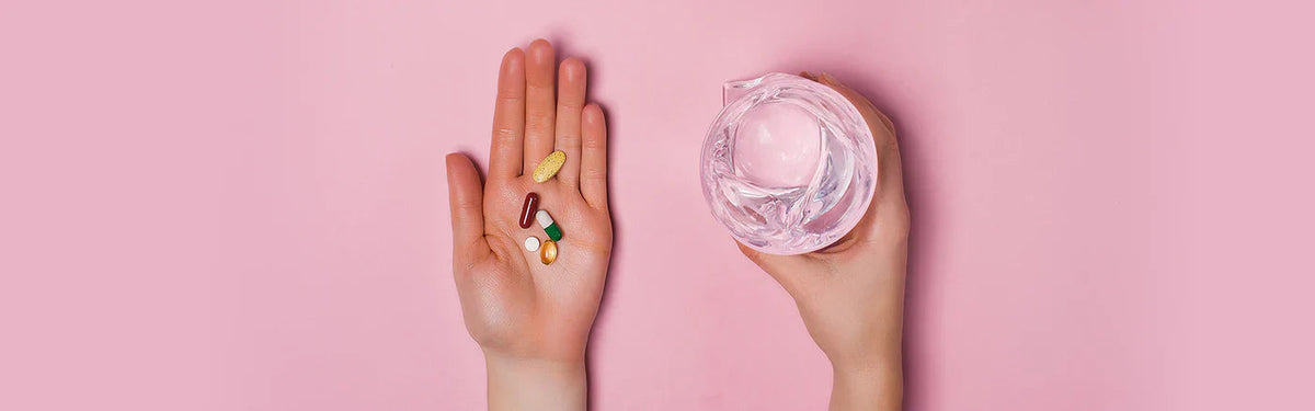 one hand with tablets and another hand with water glass