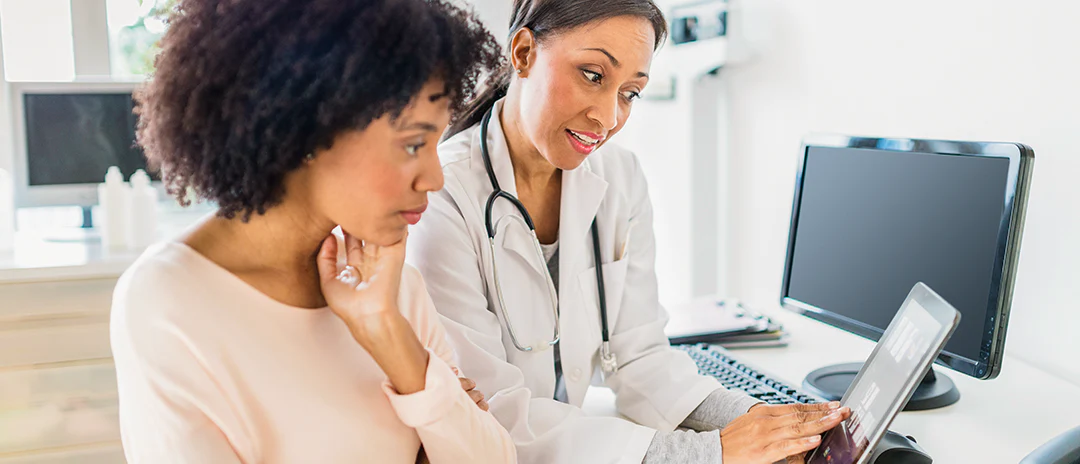 Woman and healthcare professional both looking at computer screen